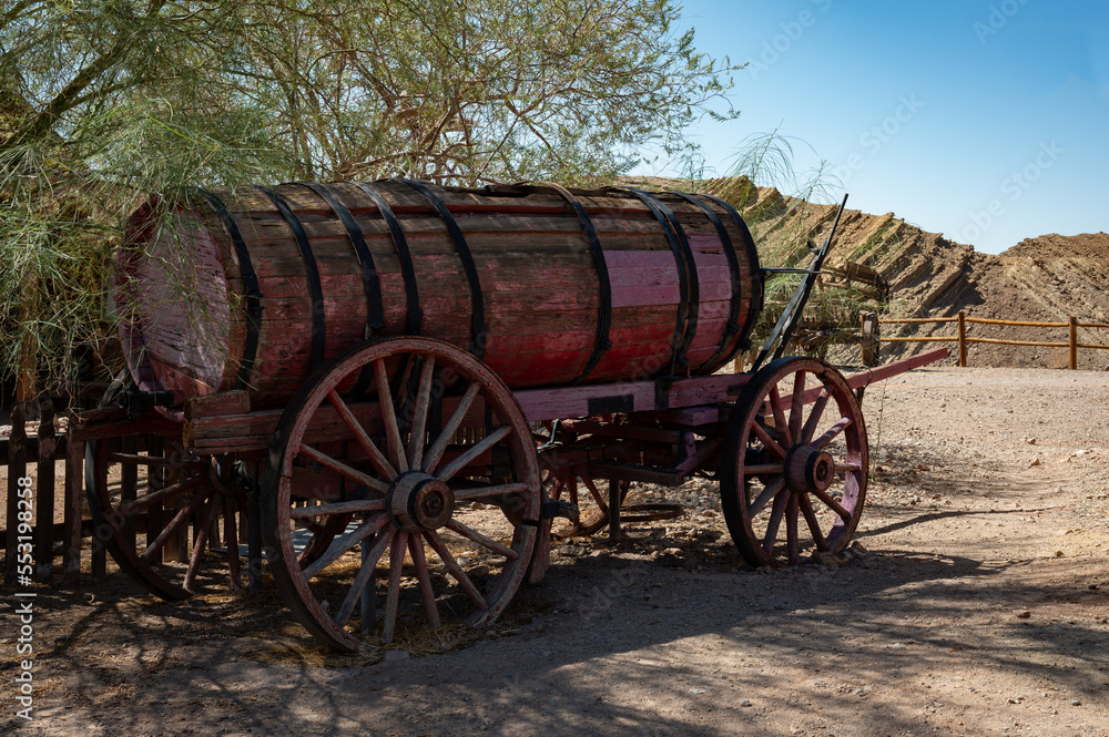 Detail of an old wooden cart with a large barrel in a town in the far west. Is abandoned