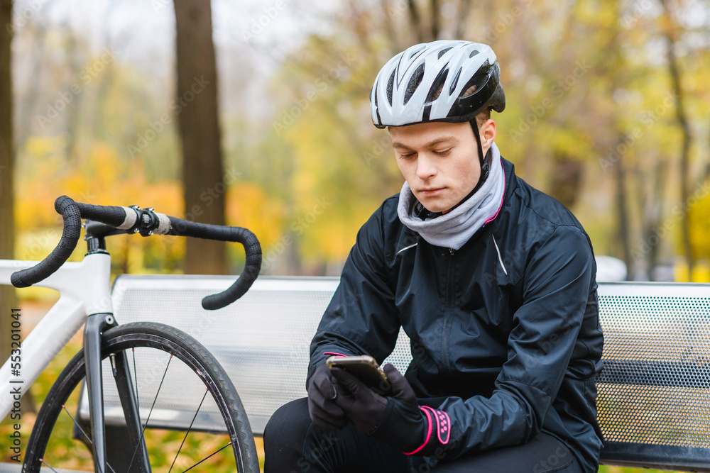 Young bicyclist relax with smartphone in park