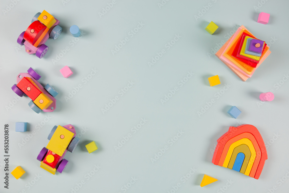 Obraz premium Baby kids toys frame background. Wooden train, colorful natural wood educational toys on light blue background. Montessori, eco-friendly toys for children. Top view, flat lay