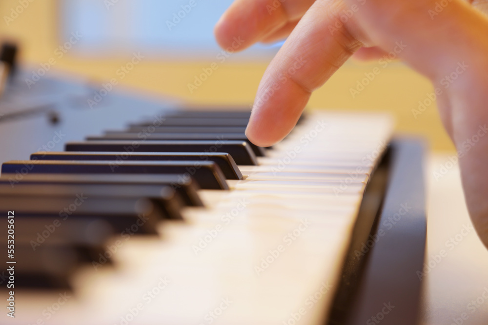 Fototapeta premium Keyboard keys close up. Right hand is going to play a note. Professional equipment for studio production. Music production and performance concept. 