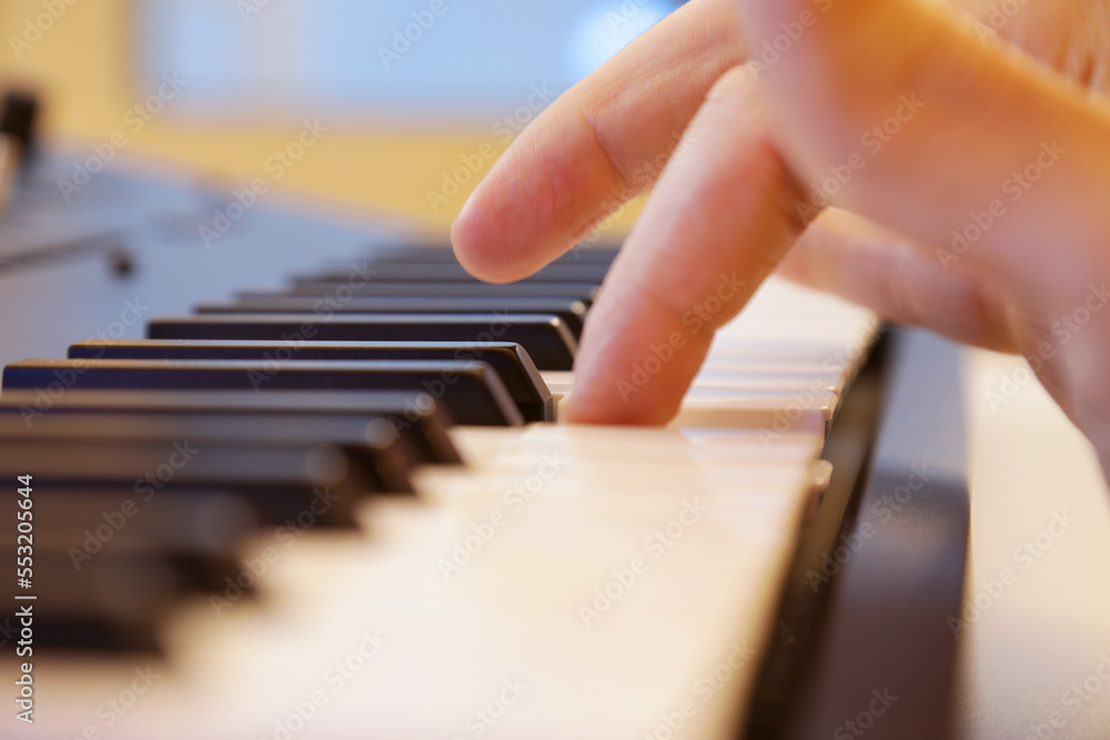 Keyboard keys close up. Right hand finger playing a note in focus. Professional equipment for studio production and live performances. Music production and performance concept.