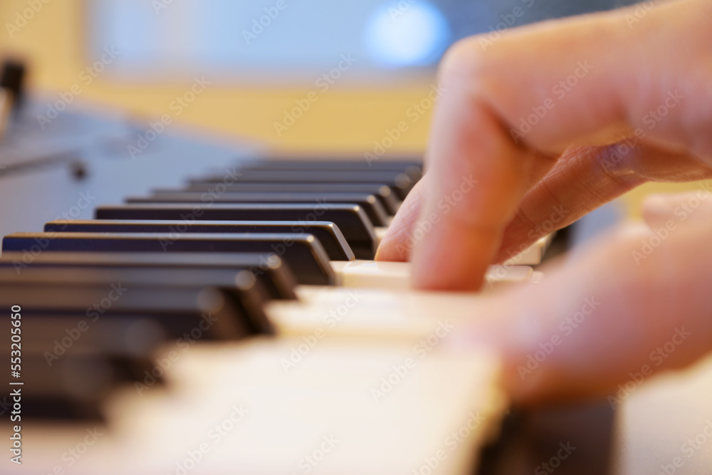 Keyboard keys close up. Right hand is playing a four note chord. Professional equipment for studio production and live performances. Music production and performance concept.
