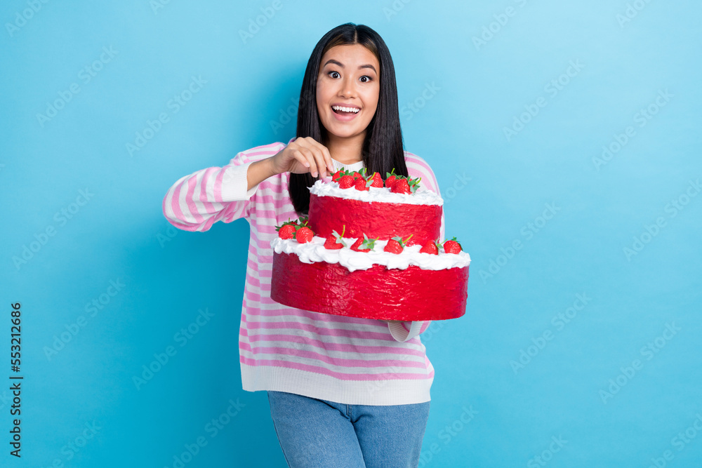 Photo of young cute pretty attractive korean woman hold baked cream with strawberries cake eat birthday food isolated on blue color background Photo of young cute pretty attractive korean woman hold baked cream with strawberries cake eat birthday food isolated on blue color background