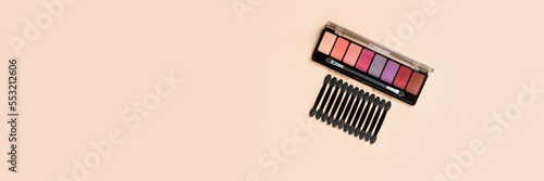 Palette of shadows with applicators on an orange background. Beauty and health. Female cosmetics for the eyes. Banner.