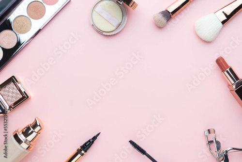 Top view of beauty cosmetic makeup accessories on pink background. Fashion woman make up product, brushes, lipstick, powder, foundation collection.