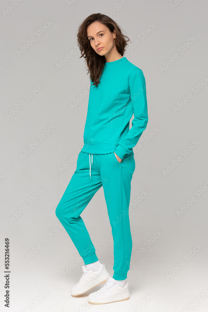 Smiling woman with thick curly hair in a mint suit of hoodies and sweatpants. Mock-up.