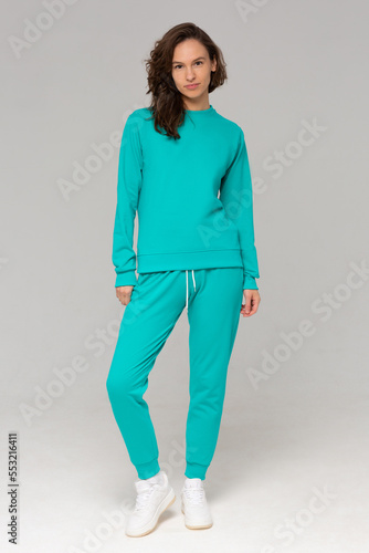 Smiling woman with thick curly hair in a mint suit of hoodies and sweatpants. Mock-up.
