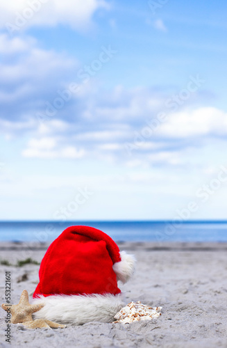 Santa Claus hat and starfish on the sandy beach