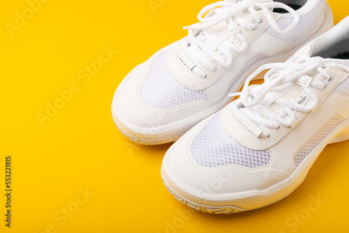 A pair of white shoes on a yellow background. White stylish sneakers. STREET STYLE.Sports concept, unisex, sports shoes, lifestyle, concept, product photo, levitation concept, streetwear.