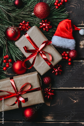 Christmass background gift boxes,red christmas tree toys,Santa hatn and spruce brance on wooden background. photo