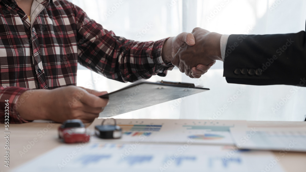 Shaking hands, Loan approver, businessman in suit, man giving car keys after car loan approval and contract signing Shaking hands, Loan approver, businessman in suit, man giving car keys after car loan approval and contract signing