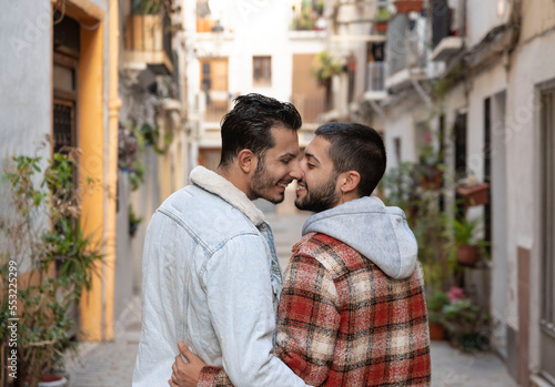 back view of gay couple walking down the street holding each other