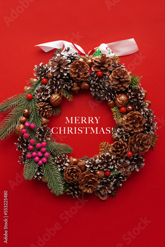 Christmas wreath with bright shiny decorations on red background