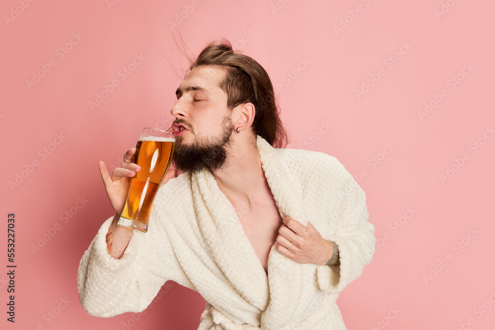 Ταπετσαρία Portrait of emotive funny man in bathrobe posing with glass of lager beer isolated on pink background