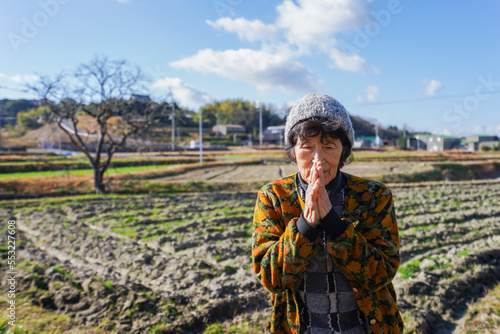 田舎でお祈りをする高齢の女性