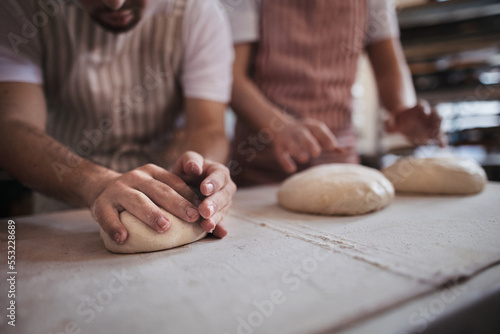 Close-up of bakers preparing fresh pastries in bakery.