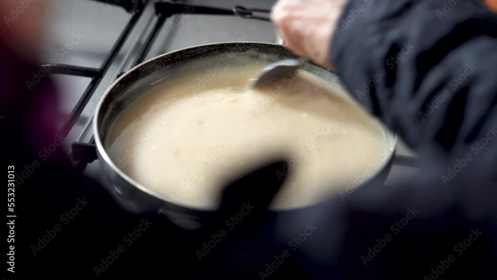 One person cooking porridge in a frying pan One person cooking porridge in a frying pan