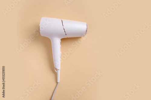 Fotografie White plastic hair dryer in on a beige background