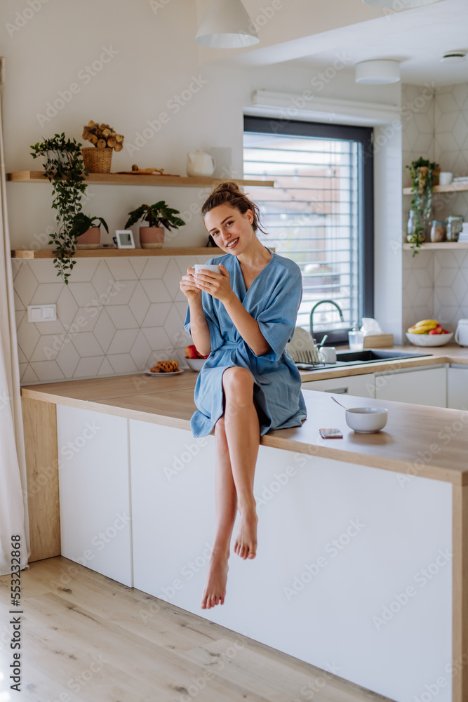 Young woman enjoying cup of coffee at morning, in her kitchen. Young woman enjoying cup of coffee at morning, in her kitchen.