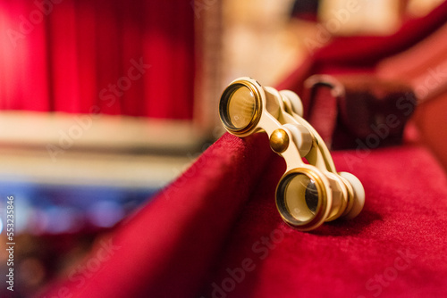Theatrical binoculars lie on a red cloth in the theater box photo