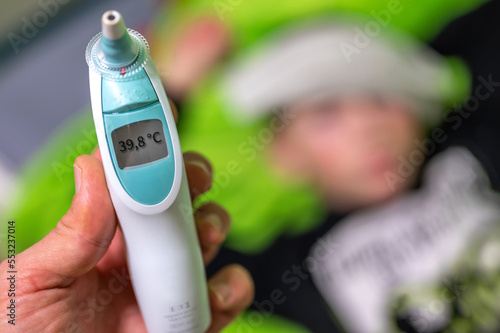Hohes Fieber bei einem Kind gemessen mit einem Ohrthermometer photo