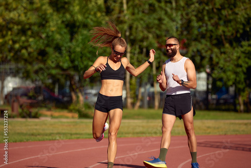 Young family promoting healthy lifestyle. Woman and man run stadium. Coach and sportsman motion run training before race. Couple runners training outdoors. Couple or family live healthy lifestyle.