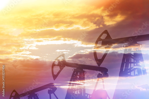 Oil production against backdrop of sunset. Rigs. Oilfield.