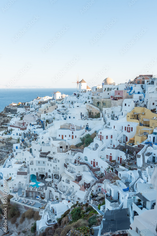 The view of Oia village at sunrise with white buildings and windmills in the background
