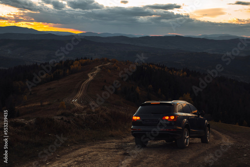 Car is going down offroad in mountains during autumn evening