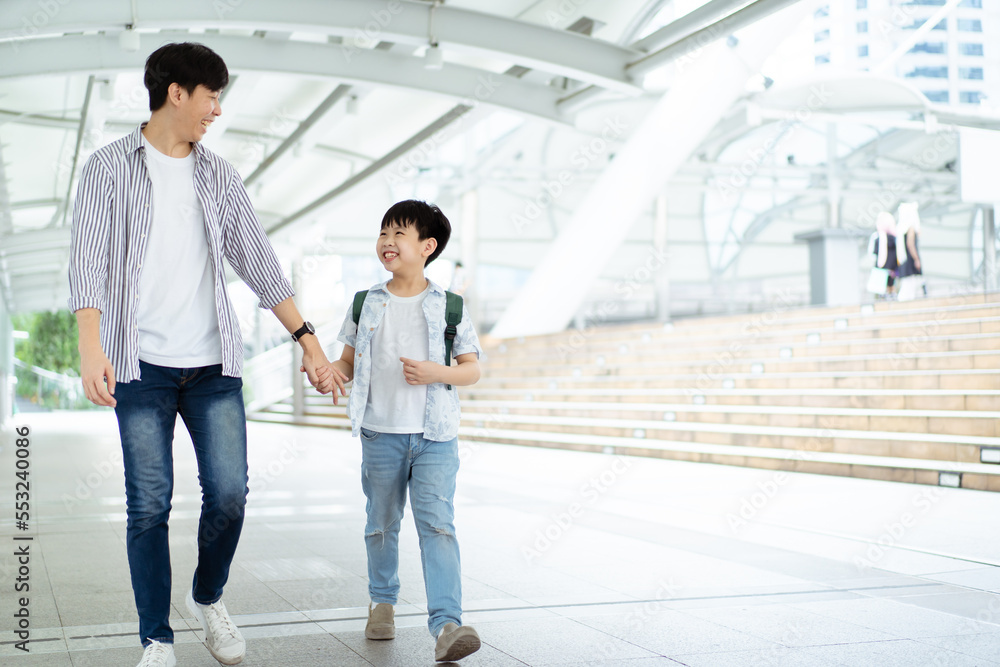 Father taking his son going to school, a man holding child hand while walking to school together. Father taking his son going to school, a man holding child hand while walking to school together.