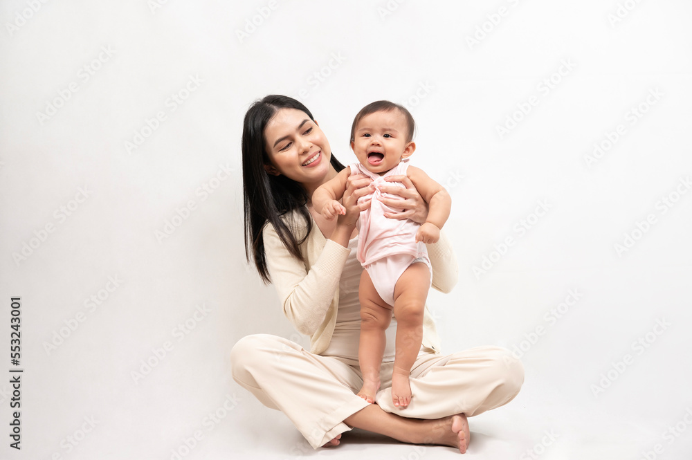 Beautiful mother and adorable baby girl are happy on white background, family, child, childhood and parenthood concept Beautiful mother and adorable baby girl are happy on white background, family, child, childhood and parenthood concept