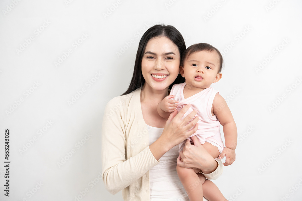 Beautiful mother and adorable baby girl are happy on white background, family, child, childhood and parenthood concept Beautiful mother and adorable baby girl are happy on white background, family, child, childhood and parenthood concept