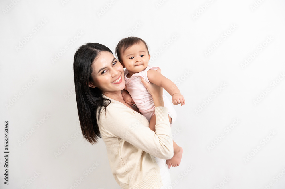 Beautiful mother and adorable baby girl are happy on white background, family, child, childhood and parenthood concept Beautiful mother and adorable baby girl are happy on white background, family, child, childhood and parenthood concept