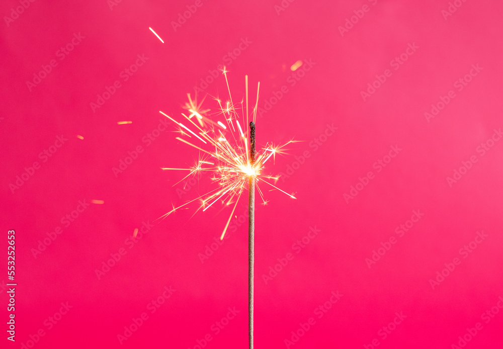 Bengal lights on a pink background. Sparkler on a bright color. Copy space. Defocus festive background. Christmas glittering sparklers