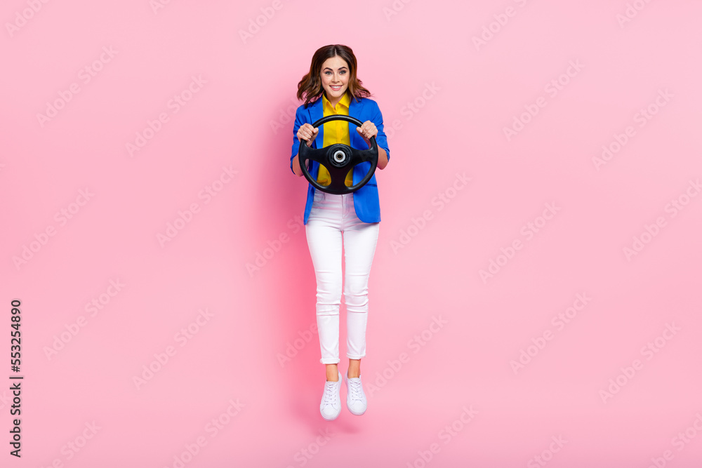 Full size photo of cheerful active girl hands hold wheel jumping have good mood isolated on pink color background Full size photo of cheerful active girl hands hold wheel jumping have good mood isolated on pink color background