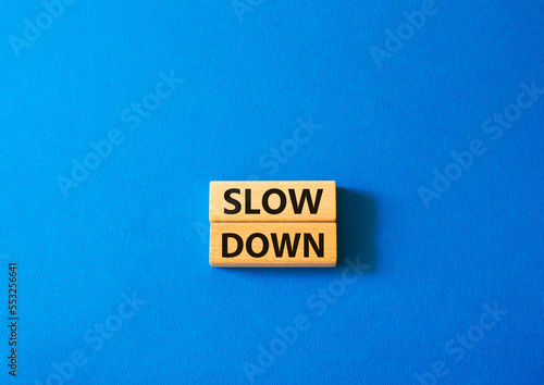Slow down symbol. Wooden blocks with words Slow down Beautiful blue background. Business and Slow down concept. Copy space.
