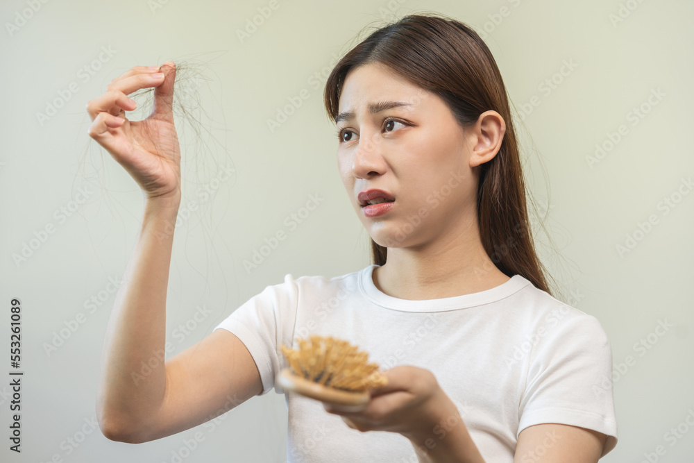 Serious, worried asian young woman, girl holding comb, show her hairbrush with long loss hair problem after brushing, hair fall out problem. Health care, beauty with copy space on white background. Serious, worried asian young woman, girl holding comb, show her hairbrush with long loss hair problem after brushing, hair fall out problem. Health care, beauty with copy space on white background.