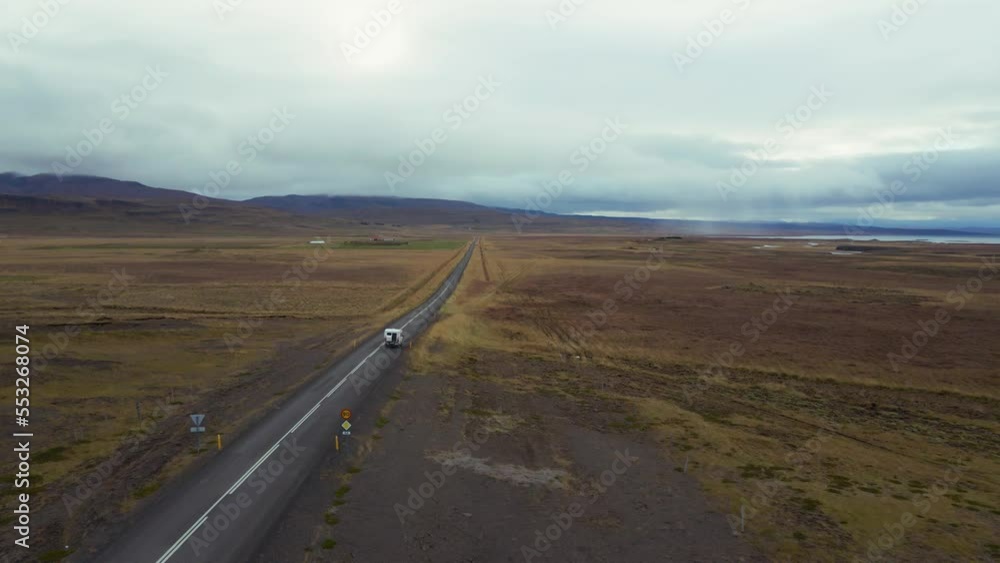 A travel van, a white colored camper is driving down a long straight road in the middle of an open landscape #2. A travel van, a white colored camper is driving down a long straight road in the middle of an open landscape #2.