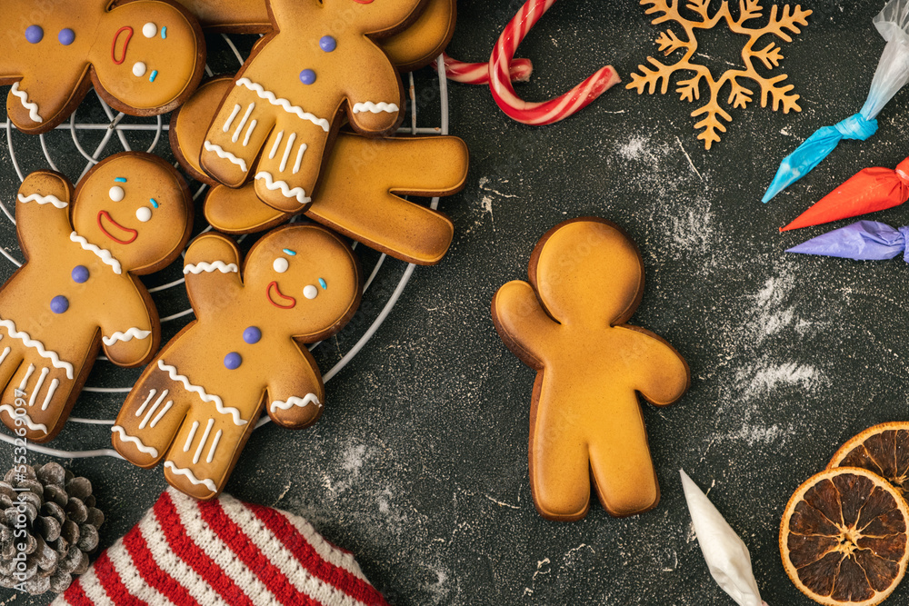 Decorating gingerbread man with white icing using pastry bag. Homemade traditional festive Christmas cookies. Flat lay. Winter holidays background. Merry Christmas and Happy New Year