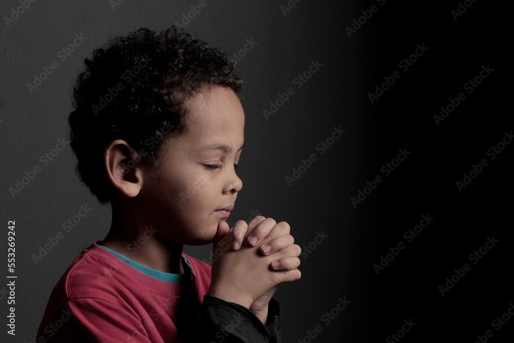 little boy praying to God with hands together with black background stock photo little boy praying to God with hands together with black background stock photo