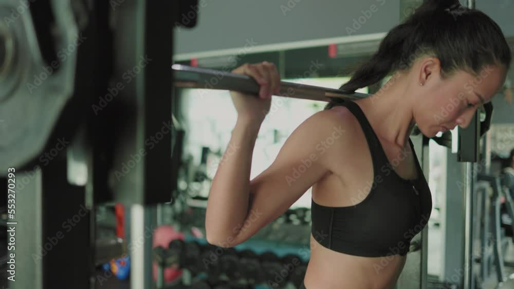 close up of Asian female athlete doing squats in gym with barbell close up of Asian female athlete doing squats in gym with barbell
