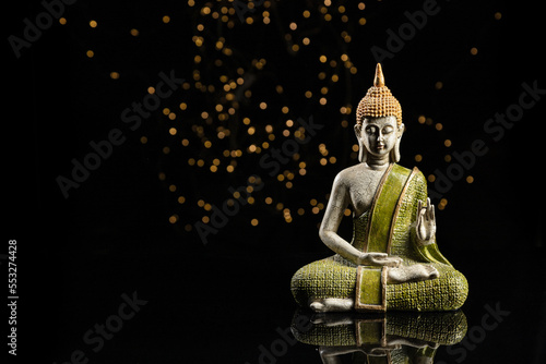 Buddha statue in meditation with lights on black background with copy space.