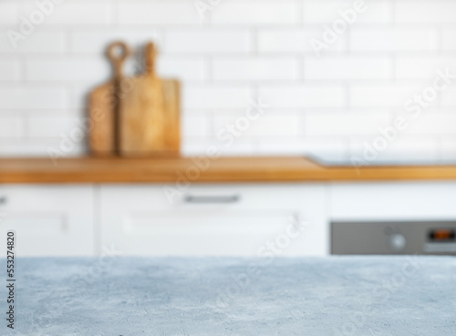 Wooden blue countertop with free space for mounting a product or layout against the background of a blurred white kitchen with cuting board.