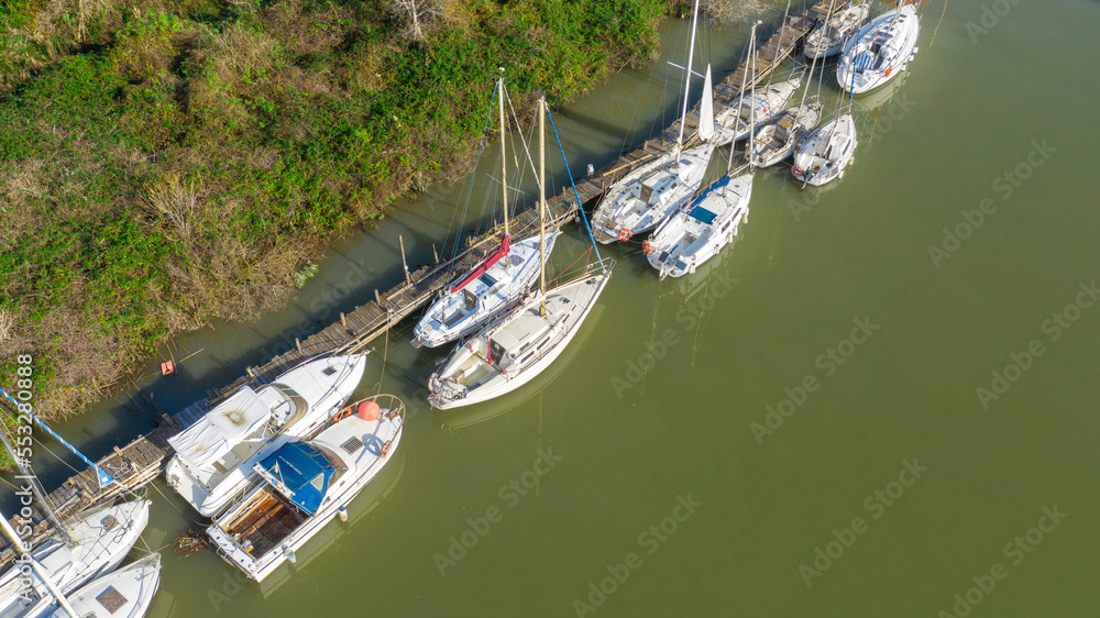 Aerial view of many small boats moored along a river.