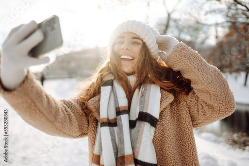 Young woman taking selfie in winter street. Holidays, rest, blogging.
