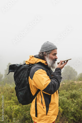 A man picks up the signal on his mobile phone and sends a voice message, Hiker with backpack talking on the cell phone during an excursion