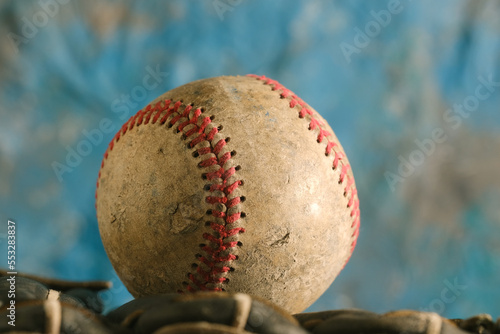 Baseball ball with old used texture closeup for sports equipment with blue blurred background.