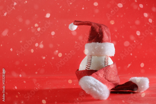 Photography Christmas holiday sports wallpaper or banner background with baseball ball in Santa outfit closeup, copy space in snow