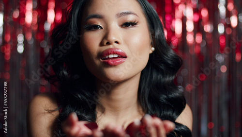Young beautiful woman blowing red confetti to a camera. Valentines. Party. New Year. Celebration. 
