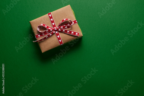 Christmas gift box wrapped in kraft paper on green background
